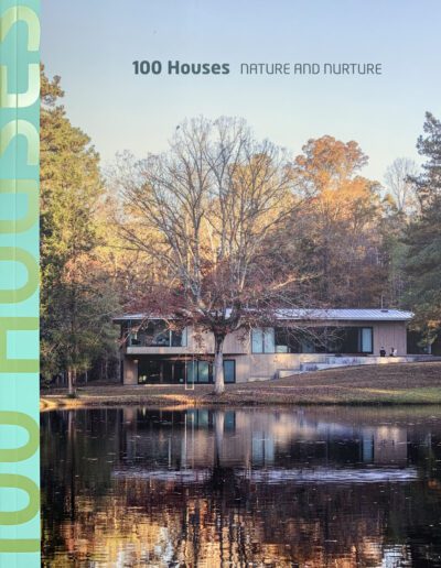 Modern house by the lakeside surrounded by trees, reflecting on water surface.