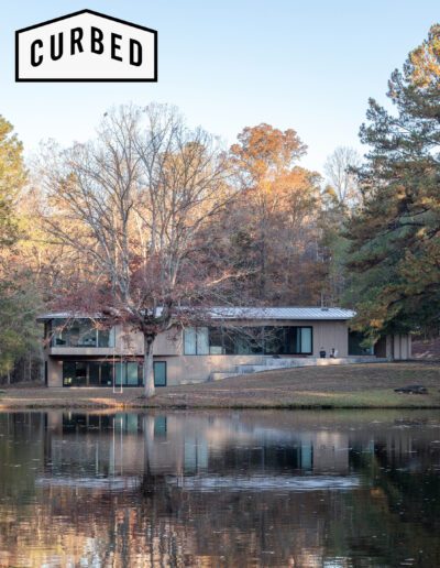Modern house by a tranquil pond surrounded by autumn foliage.