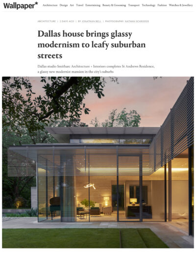 Modern house with large glass windows at dusk, showcasing interior lighting and surrounding greenery.