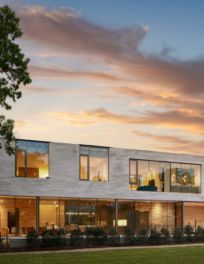 Modern building at dusk with interior lights on and a vibrant sky in the background.