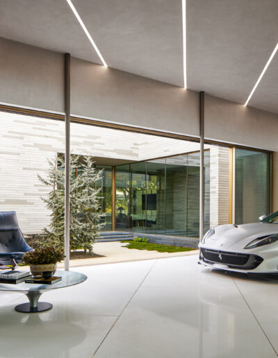 Minimalist luxury home interior featuring a sleek sports car, modern furniture, and large windows.