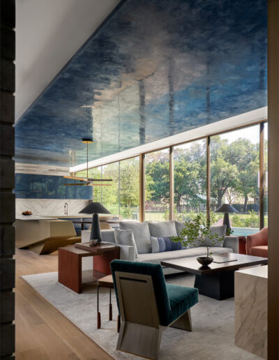 Modern living room with stylish furniture, marble accents, and a reflective ceiling that simulates a sky-like appearance.