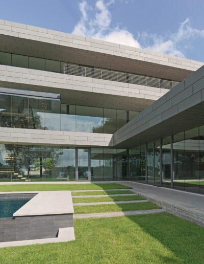 Modern building featuring extensive glass panels and linear architecture, with a reflecting pool and manicured lawn in the foreground.