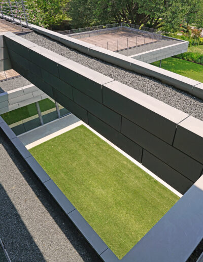 Architectural detail showing a modern building with geometric design elements, including angular walls and a green lawn on the terrace.