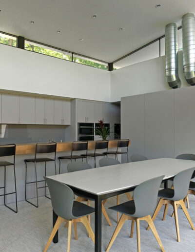 Modern kitchen and dining area with clean lines, featuring a breakfast bar, dining table, and industrial-style exposed ductwork.